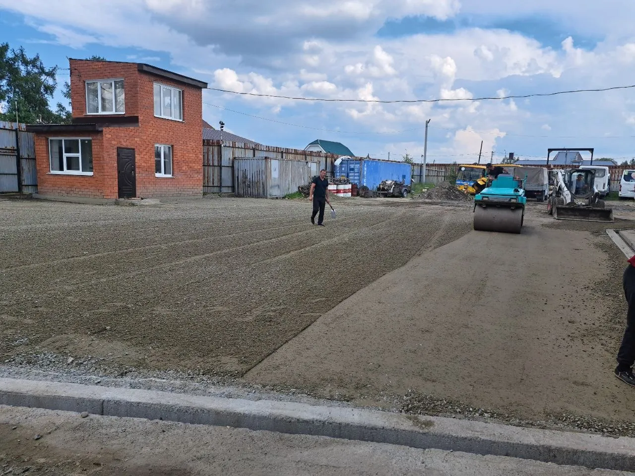 Подготовленное щебёночное основание площадки, каток и погрузчик